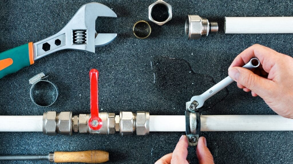 Plumber repairing a pipe valve with an adjustable wrench in Coconut Creek