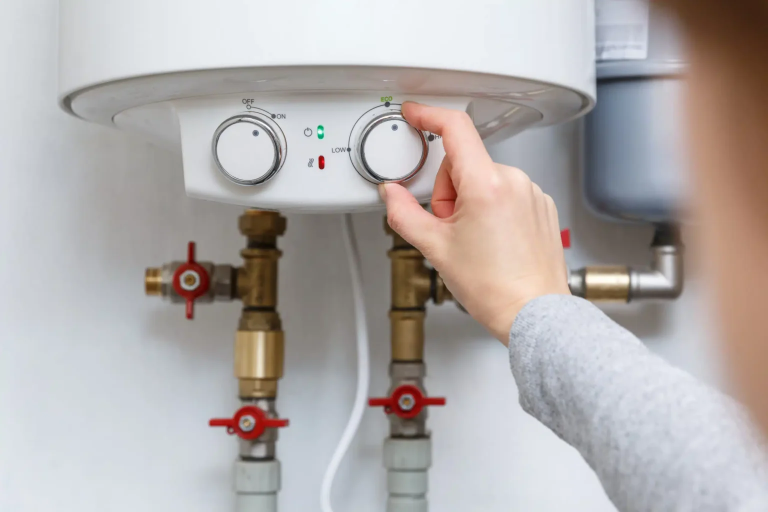 Homeowner adjusting the temperature controls on a water heater in Coconut Creek
